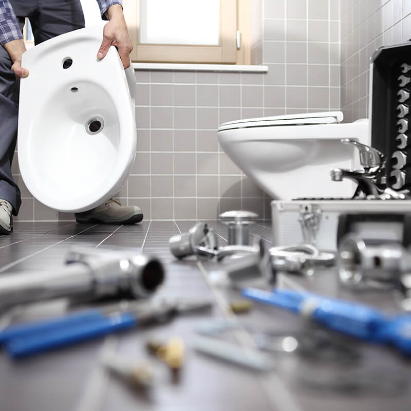 Monteur tauscht Toilette im Badezimmer aus